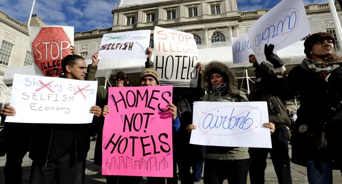 epa04571225 Detractors of Airbnb operations in New York hold signs during a rally at City Hall before a hearing on the subject of Airbnb in New York, New York, USA, 20 January 2015. The New York City Council was holding a hearing today called 'Short Term Rentals: Stimulating the Economy or Destabilizing Neighborhoods?' which was meant to examine the issue of short term rentals as handled by Airbnb. EPA/JUSTIN LANE